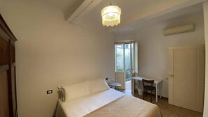 Un dormitorio con cama, escritorio y silla. Se ve un ventanal con vistas a zonas verdes.