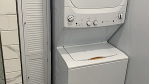 A compact, white laundry room with a built-in washer and dryer, a tall cabinet, and a tiled backsplash. - Peaceful Country Home w/Covered Bridge (Athens)