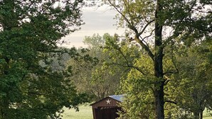 A covered bridge with a star on the roof, surrounded by trees and a paved path. - Peaceful Country Home w/Covered Bridge (Athens)