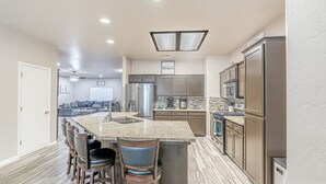 Una cocina moderna con una isla central, electrodomésticos de acero inoxidable y un área de asientos tipo barra.