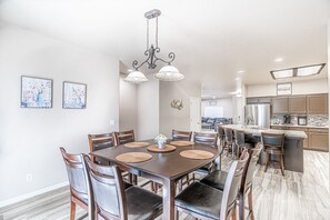 Un comedor con mesa y sillas de madera, una araña y obras de arte en las paredes.