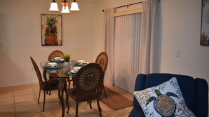 A dining area with a glass table, wooden chairs, and a blue sofa with a turtle pillow. - 3bed/2bath pool home, sleeps 8 guests, great location, private/sunny aspect. (Davenport)