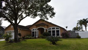 A two-story house with a brown exterior, white trim, and a large tree in front. - 3bed/2bath pool home, sleeps 8 guests, great location, private/sunny aspect. (Davenport)