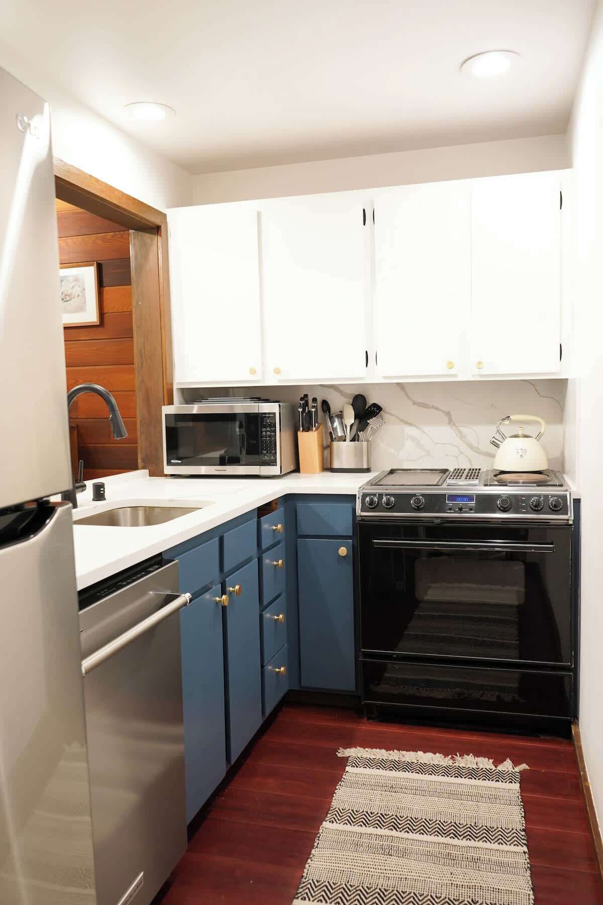 A compact kitchen with white cabinets, a microwave, a stove, and a dishwasher.