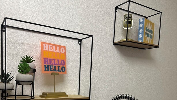 Uma cozinha com pia de aço inoxidável, bancada de madeira e prateleira de metal preto com uma placa que diz 'HELLO HELLO HELLO'.