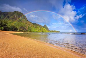 A beach with a rainbow, clear skies, and a mountainous backdrop. - A/C - Blue Ocean - Mountain & Waterfall Views (Princeville)