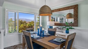 Uma área de refeições com uma mesa de madeira, cadeiras azuis e uma luminária pendente.