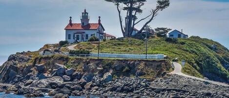 A coastal building with a lighthouse, surrounded by rocky terrain and a clear sky.