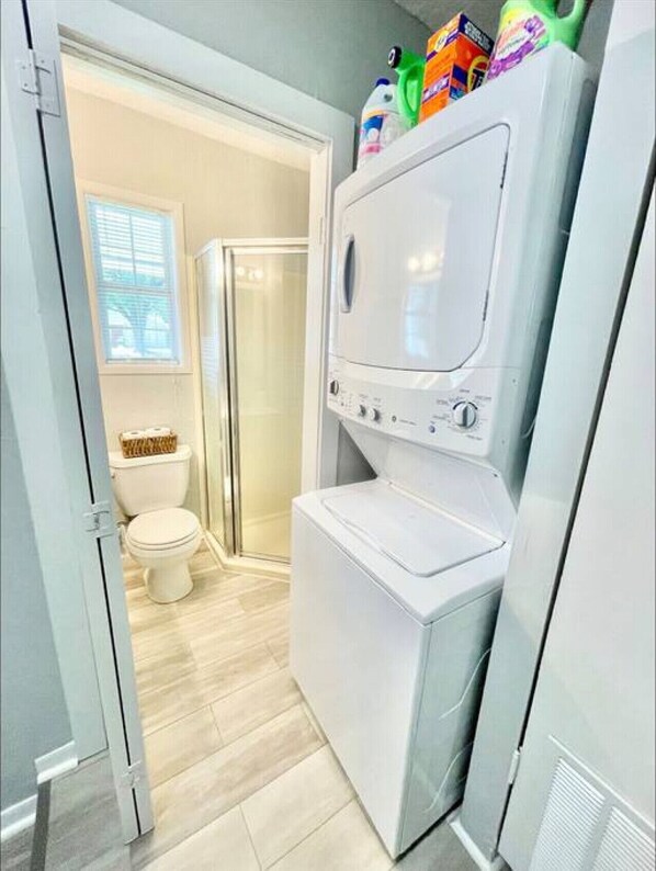 A compact bathroom with a built-in washer and dryer, a toilet, and a shower.