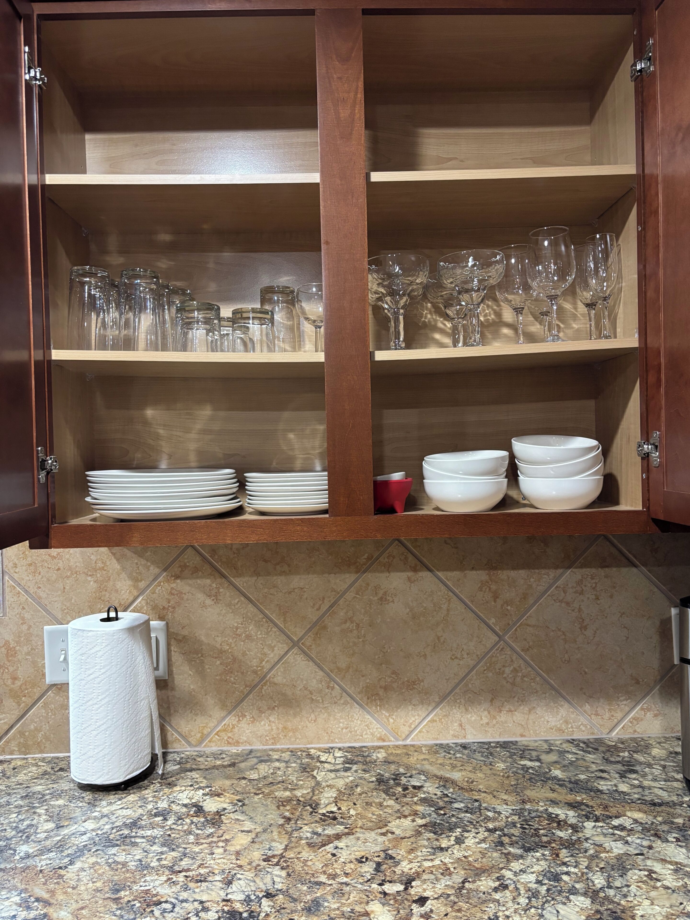 Un meuble de cuisine avec des étagères où sont rangés des verres et des assiettes.