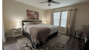 A bedroom with a bed, nightstands, a ceiling fan, a window with curtains, and a chair. - A Family Cozy Getaway 7 miles from Sea World and Fiesta, Texas (San Antonio)