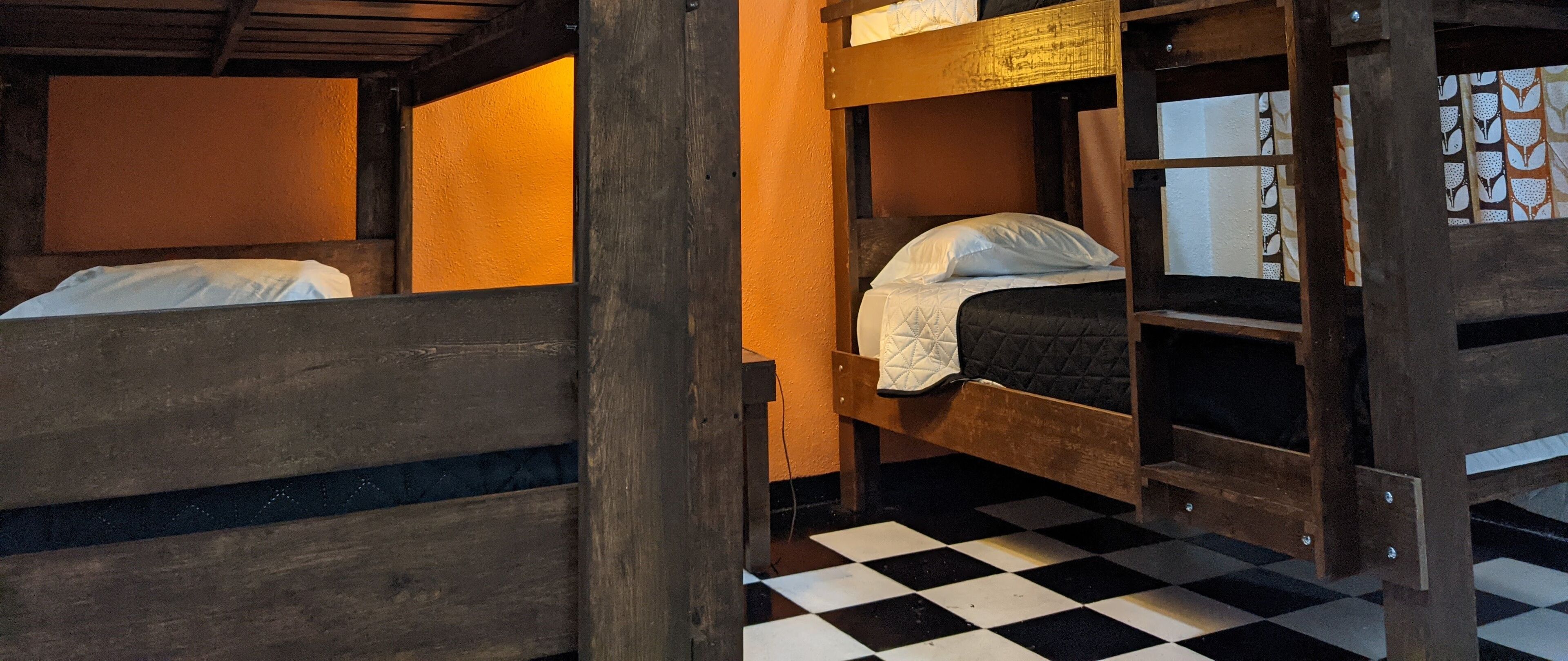 A room with two bunk beds, wooden walls, and a checkered floor.