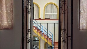 Una puerta abierta que da a una escalera con barandilla amarilla y barandilla azul.