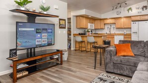 A modern living room with a flat-screen TV, a sofa, and a coffee table. - Borealis Abode: Abundant Amenities; Private Hot Tub, Pool Table, and King Bed (North Pole)
