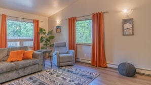 A living room with a sofa, armchair, and a patterned rug. - Borealis Abode: Abundant Amenities; Private Hot Tub, Pool Table, and King Bed (North Pole)