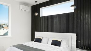 Un dormitorio moderno con una cama grande, un ventanal y un espejo integrado.