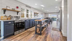 A modern kitchen with dark cabinets, stainless steel appliances, and wooden flooring. - Honeysuckle Beach House - Next to Shady Gators - Private Beach! (Lake Ozark)