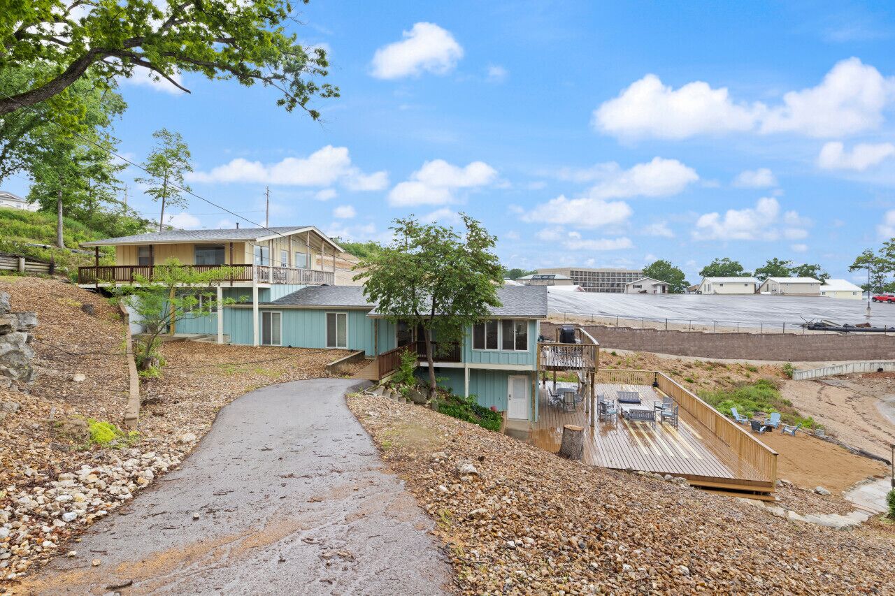A coastal property with a paved driveway, a wooden deck, and a view of the beach.