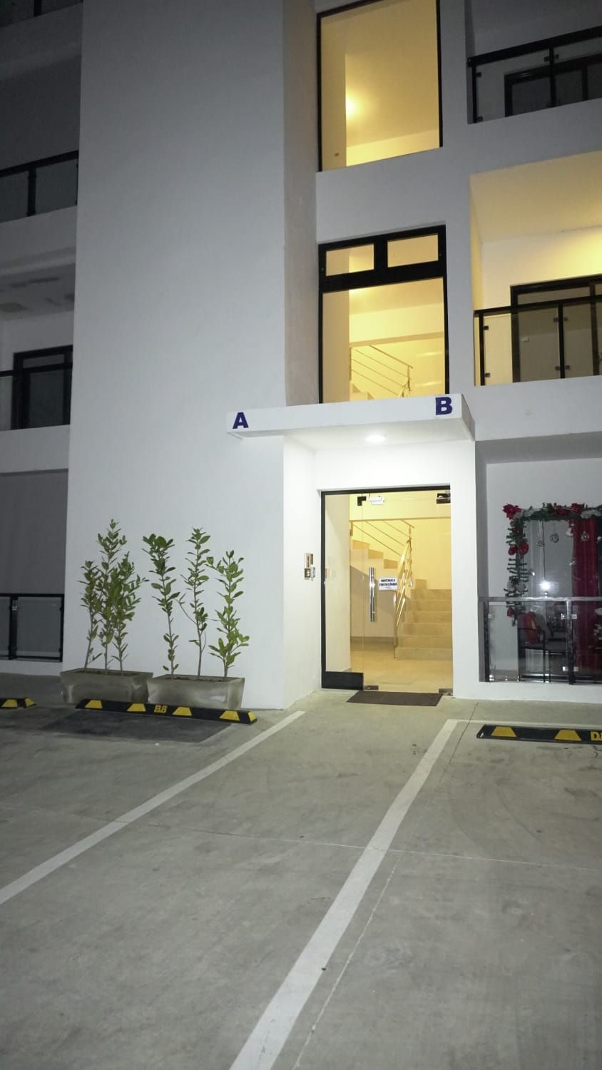 A modern building with a flat facade, a ground-level entrance, and a staircase leading to an upper level.