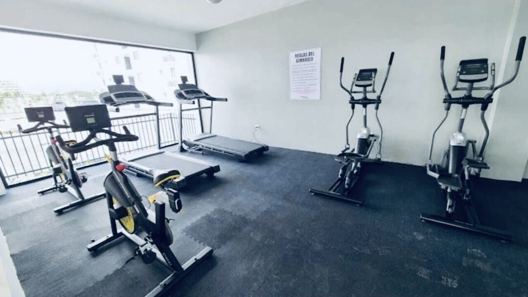Una palestra con tapis roulant, cyclette e vogatore.