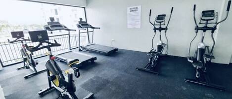 Una palestra con tapis roulant, cyclette e vogatore.