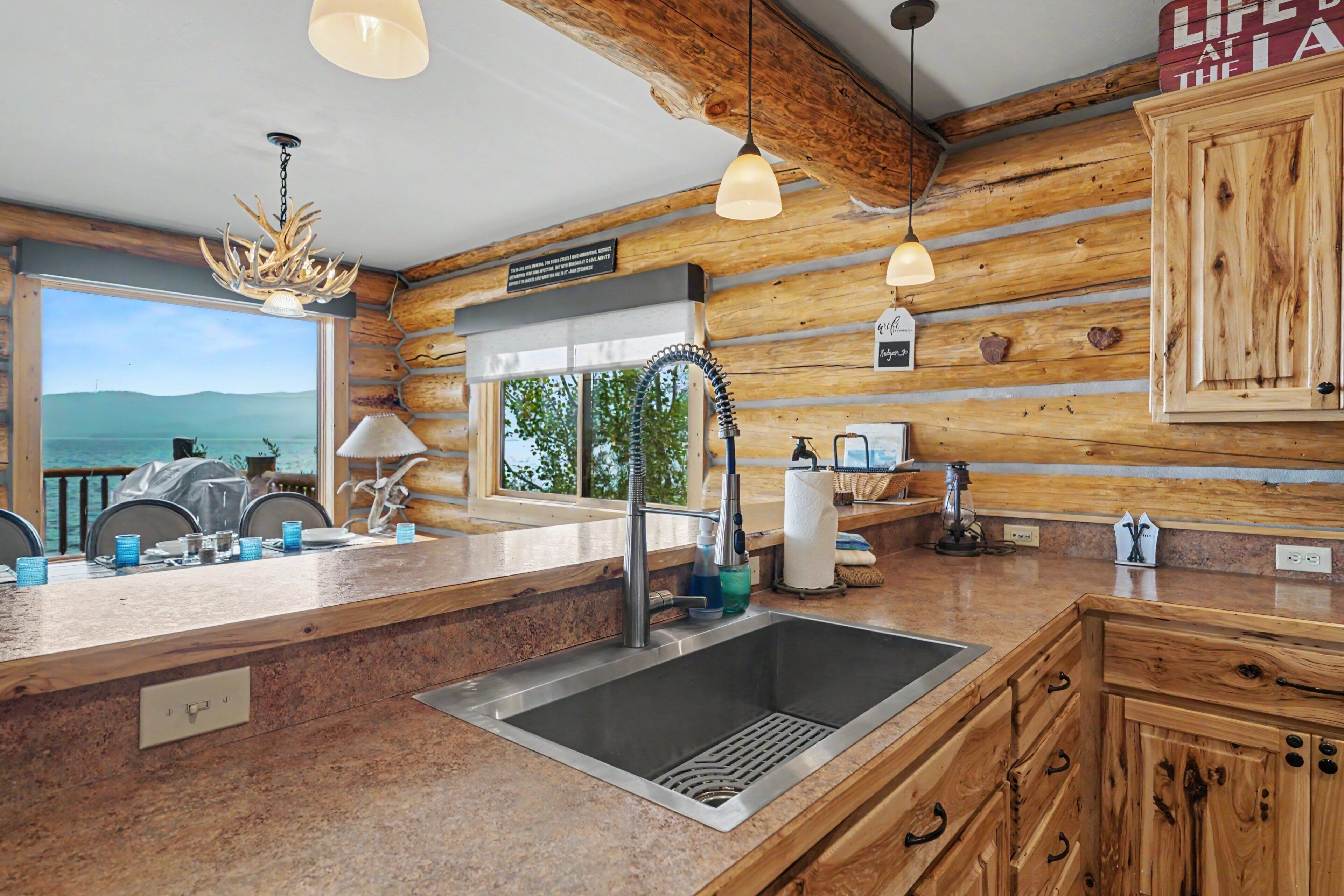 A kitchen with a granite countertop, stainless steel sink, and wooden cabinetry.