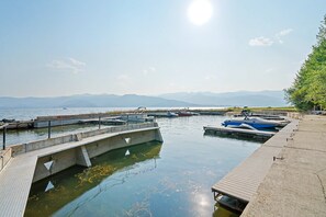 Ein Yachthafen mit vertäuten Booten, eine Betonsteg und ein freier Blick auf das Wasser und die entfernten Berge.