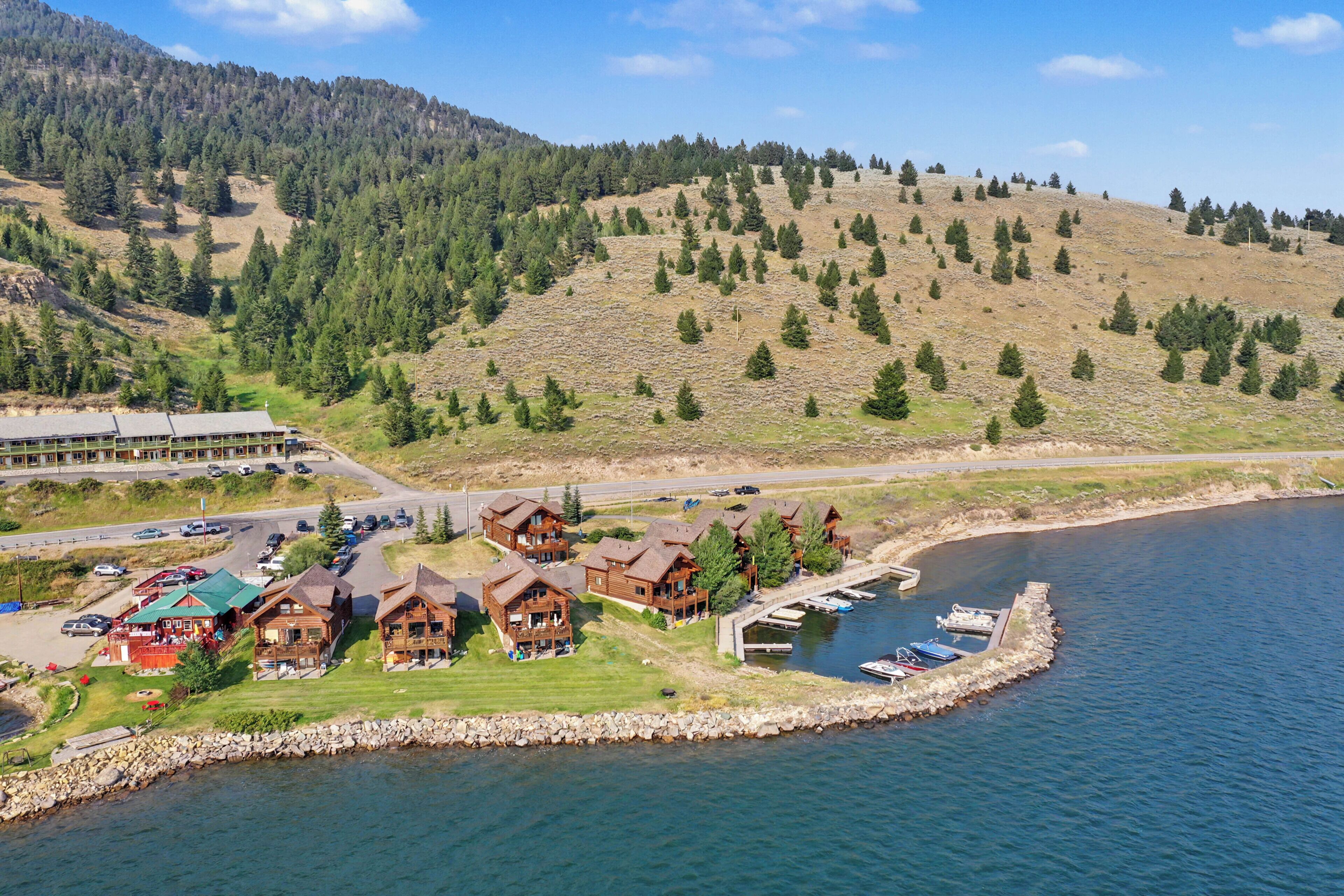 Un lodge sul lago con diverse cabine, un molo e una strada che porta a un’area di parcheggio.