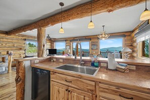 Una cocina rústica con vigas de madera, un ventanal grande y un lavavajillas empotrado.