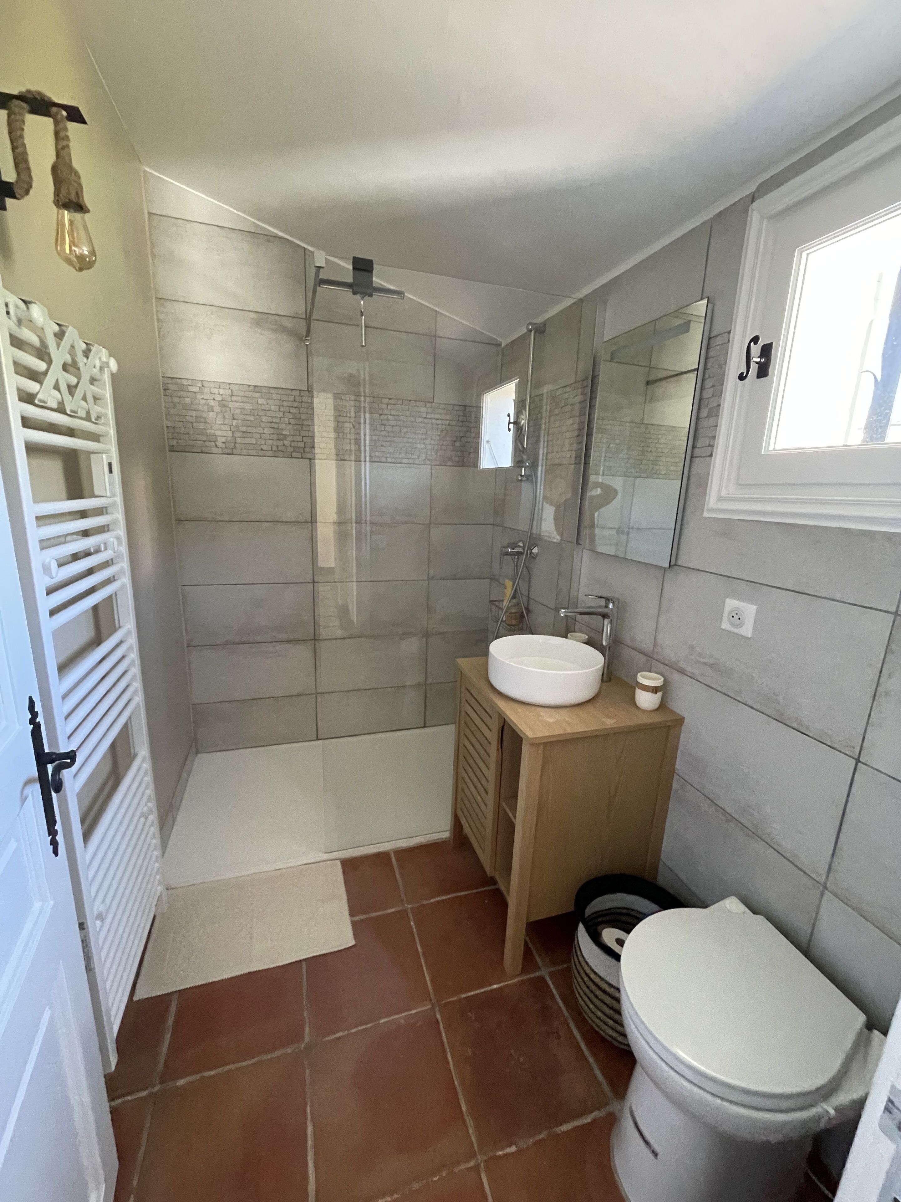 Um banheiro moderno com chuveiro de vidro, um lavatório de madeira com pia e vaso sanitário.