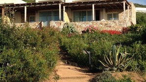 A two-story building with a stone facade, a covered patio, and a pathway leading to the entrance. - Mini Villa avec imprenable vue sur la mer (Lumio)