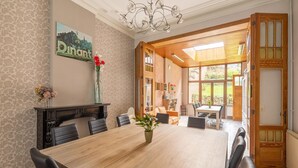 A dining area with a large wooden table, black chairs, a vase with flowers, and a chandelier. - Beautiful holiday home in Dinant with garden (Dinant)