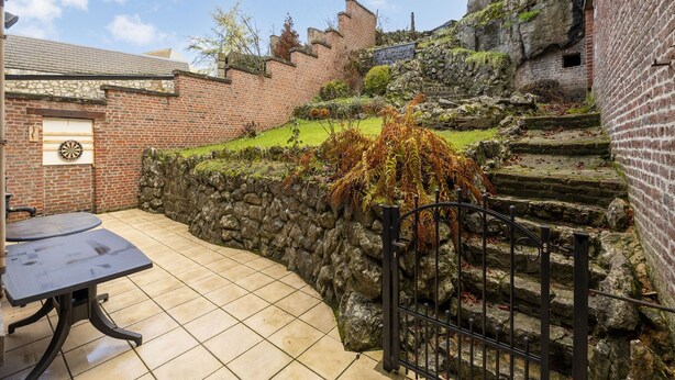 A courtyard with a table and chairs, stone walls, and a staircase leading up to a building. - Beautiful holiday home in Dinant with garden (Dinant)