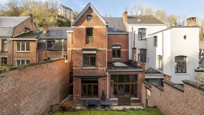 A traditional brick house with a central entrance, a small patio, and a white building adjacent to it. - Beautiful holiday home in Dinant with garden (Dinant)