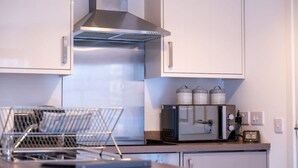 A modern kitchen with stainless steel appliances, a built-in oven, and a coffee machine. - Talisker Apartment in Oban Town Centre (Argyll and Bute Council)