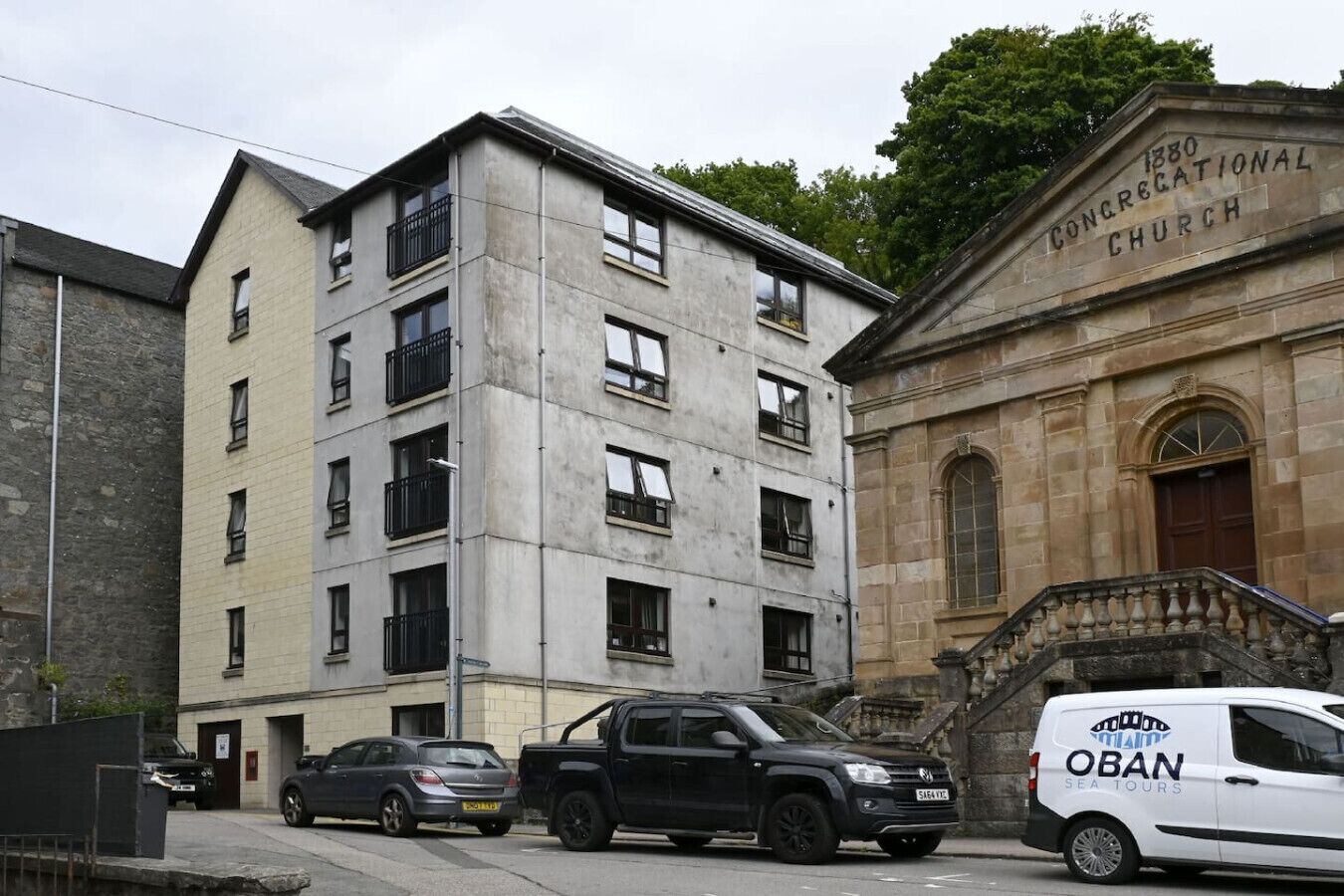 Un edificio de varios pisos con fachada de piedra y un letrero que dice '1880 Congregational Church'.