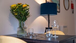 A dining table with a vase of yellow flowers, two wine glasses, and cutlery. - Springbank Apartment in Oban Town Centre (Oban)