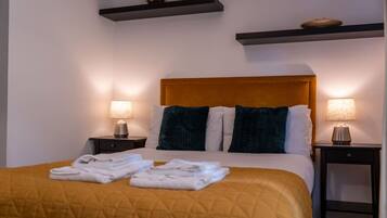 Una habitación de hotel con una cama, dos mesitas de noche y dos estantes fijados a la pared.