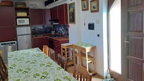 Cocina compacta con comedor, que incluye un microondas, refrigerador y armarios de madera.