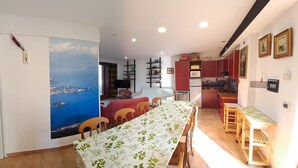 Un comedor con una larga mesa, sillas y vistas a un paisaje costero.
