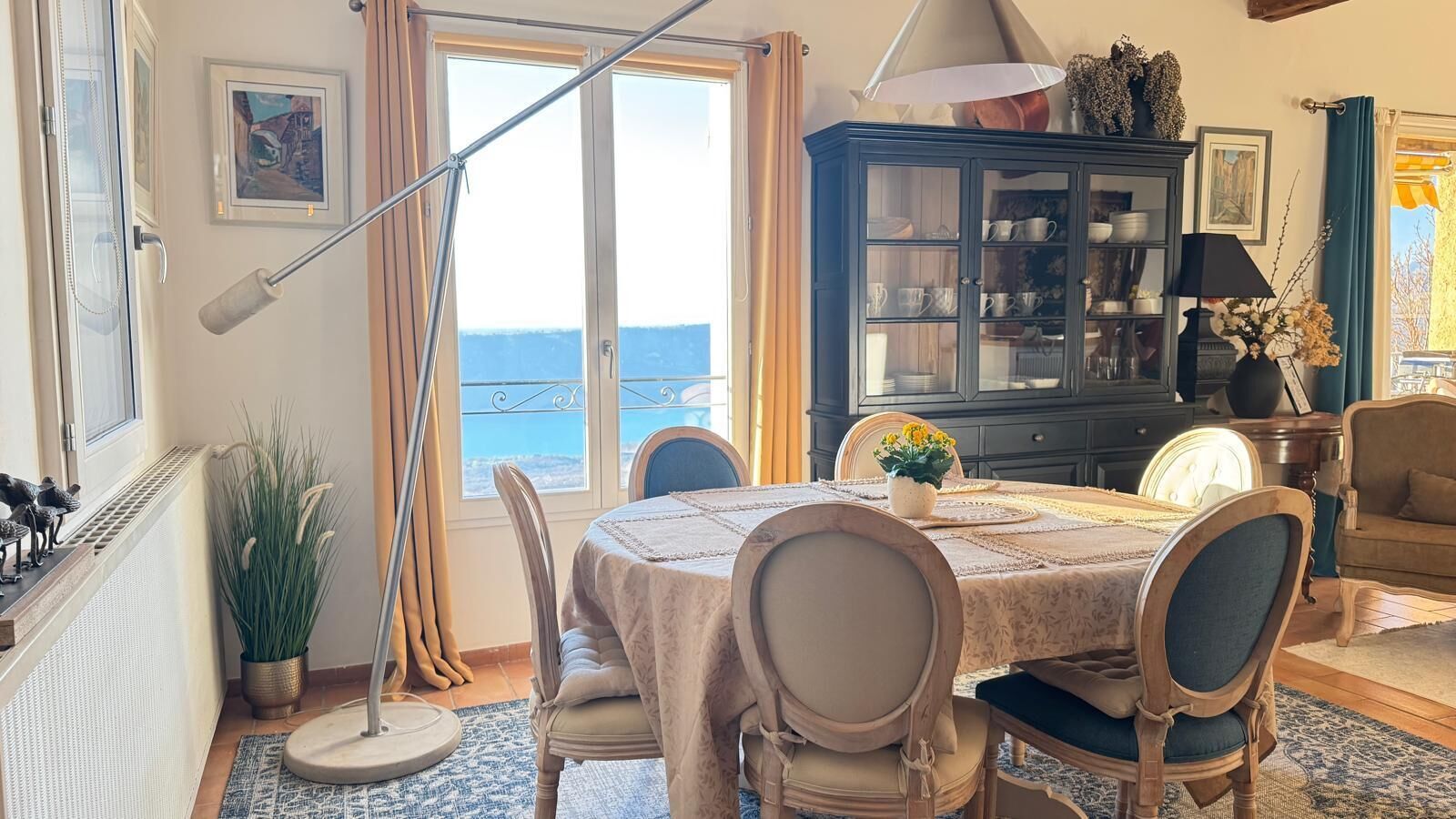 Un espace repas comprenant une table, des chaises, un buffet et une vue sur la mer.