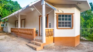 A building with a covered porch, a single window, and a sign that reads "WELCOME". - Eleven30 Luxury Apartments  (Negril)