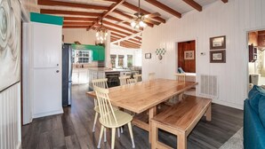 Ein geräumiger Essbereich mit Holztisch und Stühlen, Deckenventilator und Blick in die Küche.