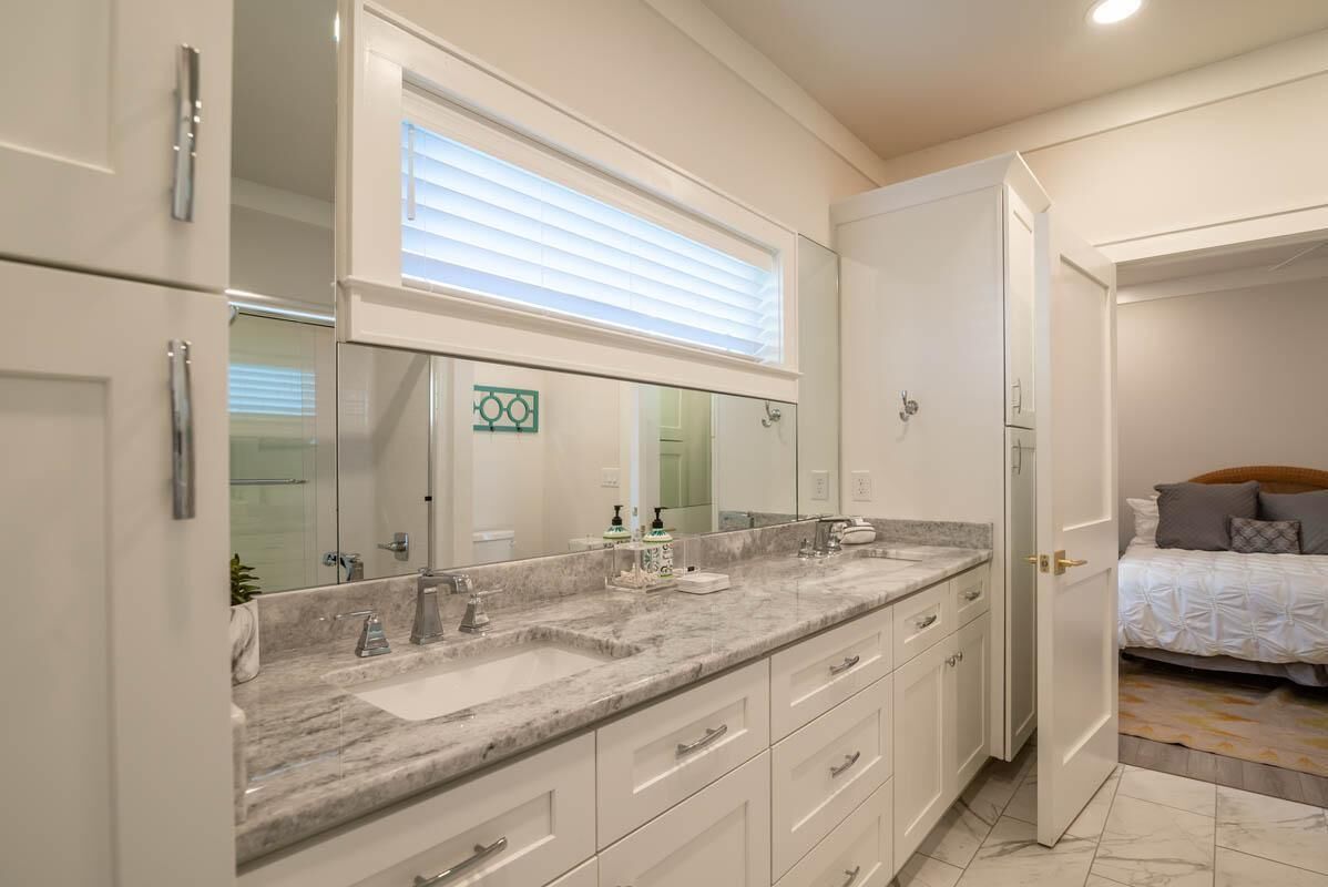 A modern bathroom with a large vanity, a mirror, and a window above the sink.