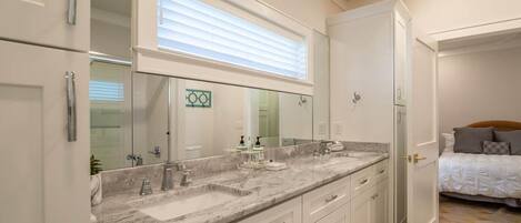 A modern bathroom with a large vanity, a mirror, and a window above the sink.