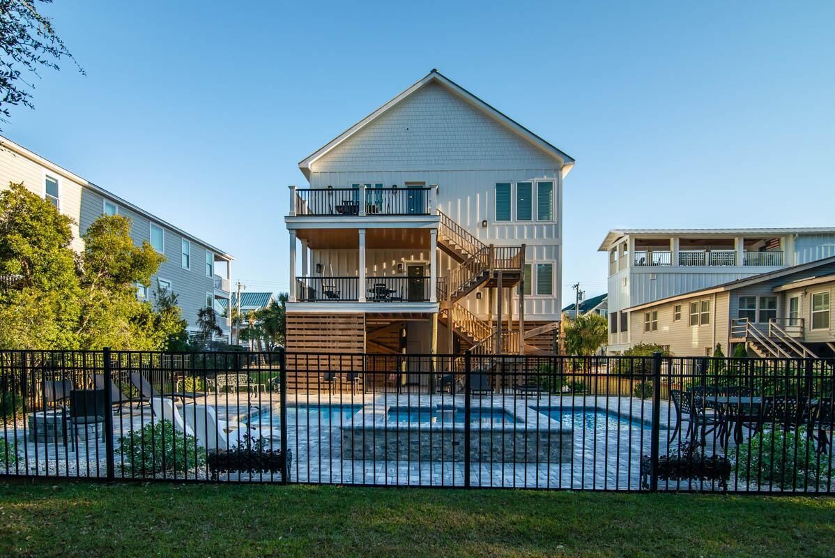 A two-story building with a balcony, a swimming pool, and a fenced area.