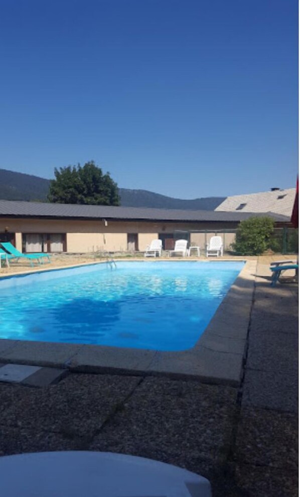 Piscine extérieure en saison, parasols, chaises longues