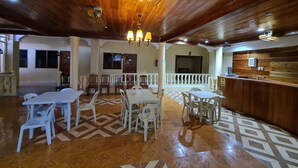 A spacious indoor area with wooden ceiling beams, a patterned floor, and several tables and chairs arranged for dining or meetings. - La-Familia Guest House (Siquijor)