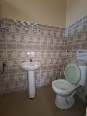 A bathroom with a white sink, toilet, and a shower area.