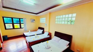A hotel room with three beds, a window with a view, an air conditioning unit, and a ceiling with fluorescent lights. - La-Familia Guest House (Siquijor)
